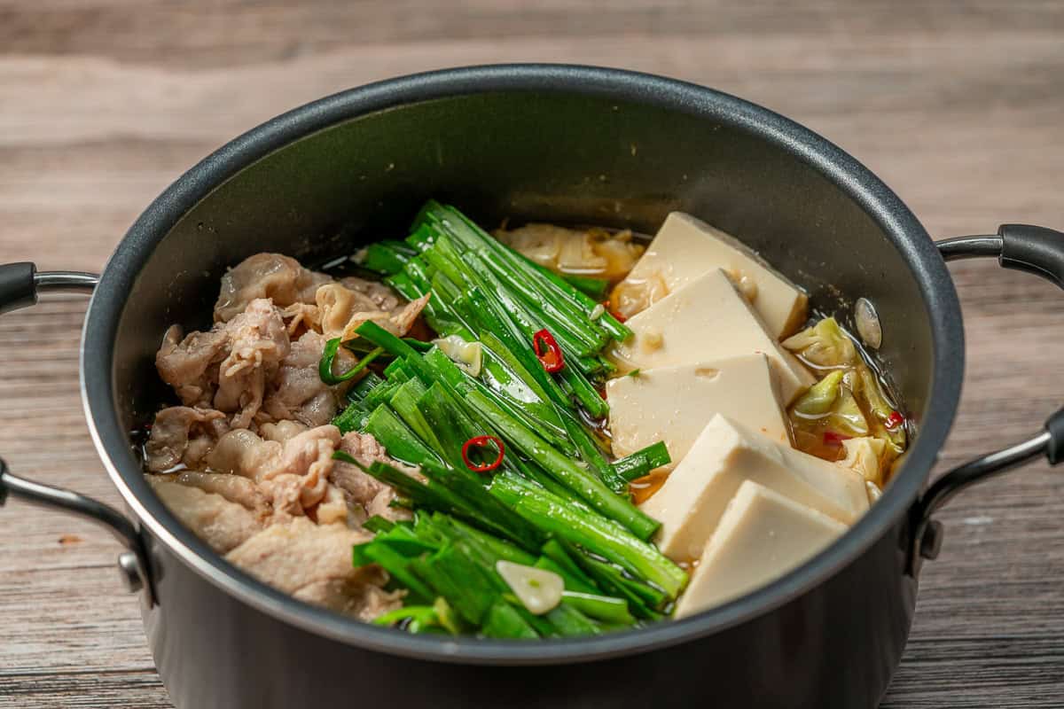 A pot of Pork Belly & Cabbage Nabe Hot Pot with pork, nira, and tofu