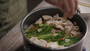 Sprinkling sesame seeds on Pot with nira, tofu, cabbage, and tofu