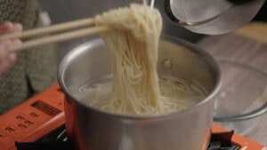 Cooking ramen noodles in pot of boiling water